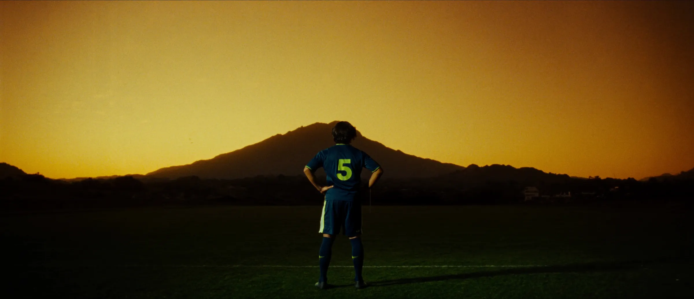 Jugador solo en cancha al atardecer mirando el volcán Ilaló
